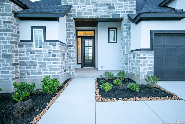 entrance to property with stone siding, an attached garage, roof with shingles, and stucco siding