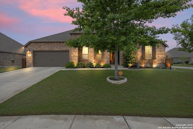 view of front facade featuring an attached garage, brick siding, a yard, and concrete driveway