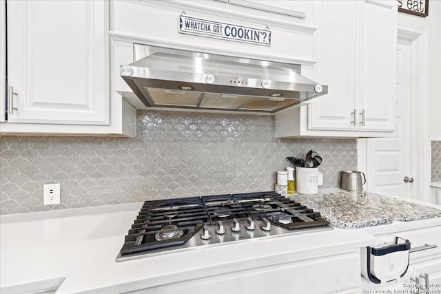kitchen with white cabinets, decorative backsplash, under cabinet range hood, and light countertops