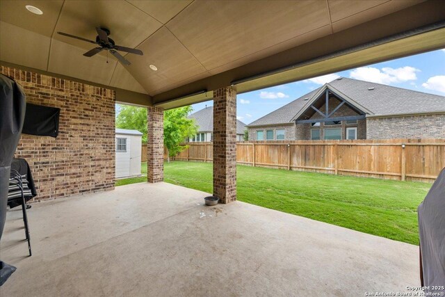 view of patio / terrace with a fenced backyard, an outdoor structure, a storage unit, and ceiling fan