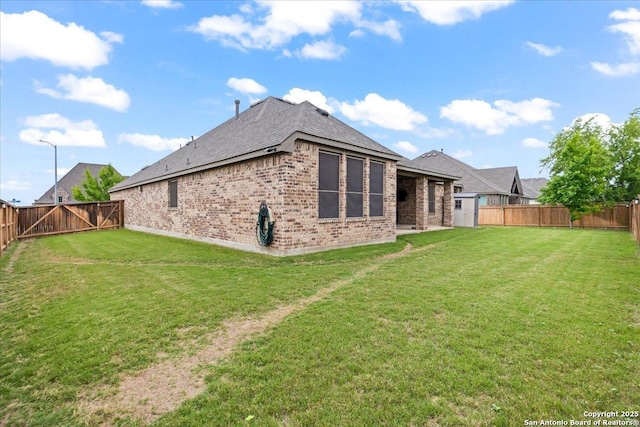 rear view of house with brick siding, a yard, roof with shingles, and a fenced backyard