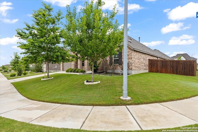 view of front of home featuring fence, a front lawn, and brick siding