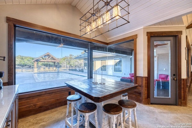 dining space featuring wood ceiling, vaulted ceiling, and a wainscoted wall