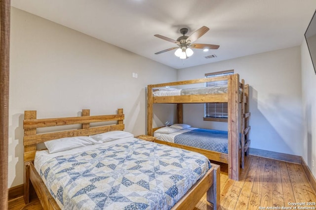 bedroom with wood finished floors, visible vents, a ceiling fan, and baseboards