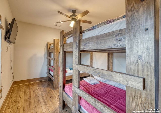 bedroom featuring hardwood / wood-style flooring, ceiling fan, baseboards, and visible vents