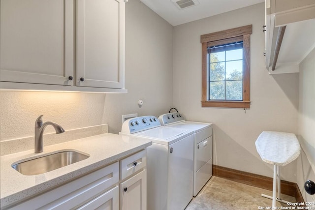 clothes washing area with washer and clothes dryer, visible vents, a sink, baseboards, and cabinet space