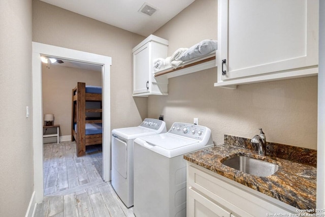 67 Stepping Stone, Concan, TX 78838 - washroom with a sink, light wood-style floors, cabinet space, washing machine and dryer, and visible vents