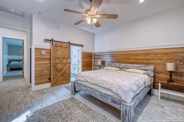 67 Stepping Stone, Concan, TX 78838 - bedroom featuring a barn door, visible vents, recessed lighting, wood finished floors, and ceiling fan