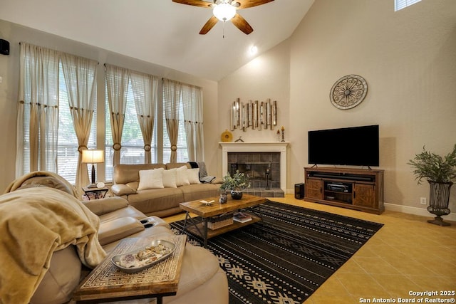 tiled living area with a tiled fireplace, baseboards, ceiling fan, and high vaulted ceiling