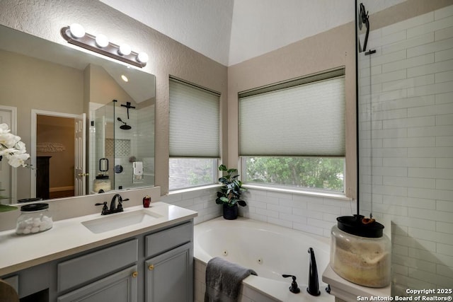 bathroom with vanity, a shower stall, lofted ceiling, and a jetted tub
