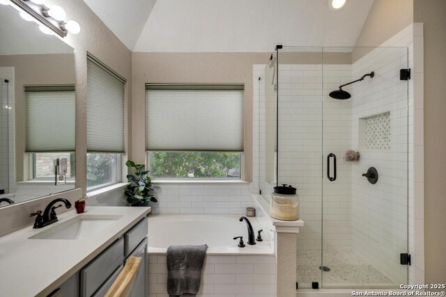 bathroom featuring vanity, vaulted ceiling, a stall shower, and a bath