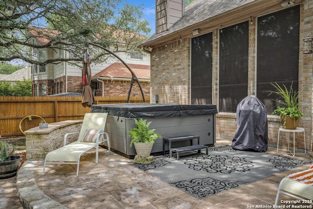 view of patio / terrace featuring a hot tub and fence