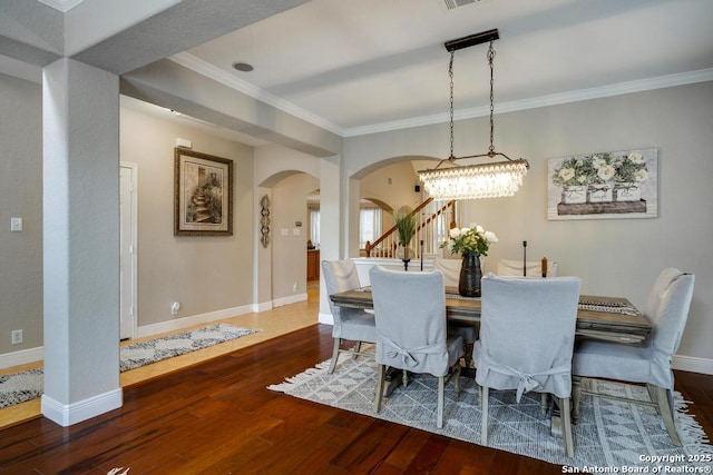 dining room with arched walkways, baseboards, and hardwood / wood-style flooring