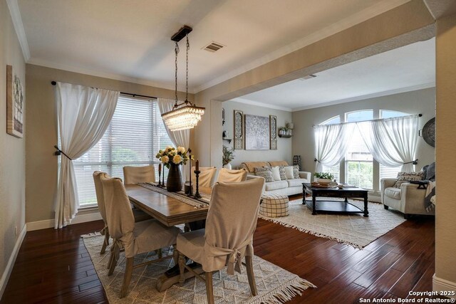 dining space with visible vents, dark wood finished floors, baseboards, an inviting chandelier, and ornamental molding
