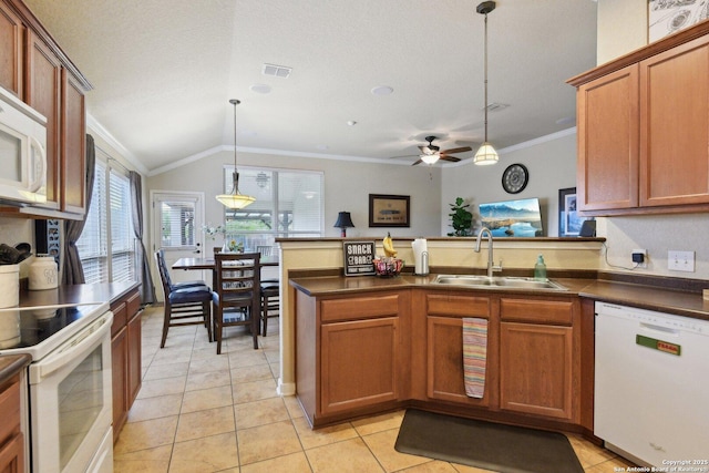 kitchen featuring dark countertops, white appliances, a sink, and crown molding