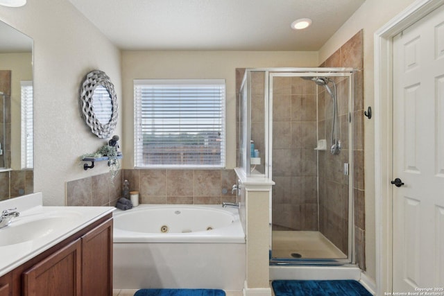bathroom featuring vanity, a stall shower, and a tub with jets