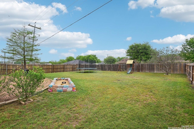view of yard featuring a trampoline, a fenced backyard, and a playground
