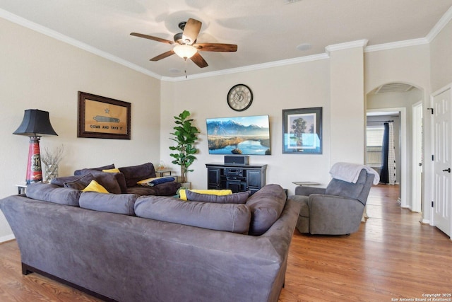 living room with wood finished floors, ornamental molding, baseboards, and ceiling fan