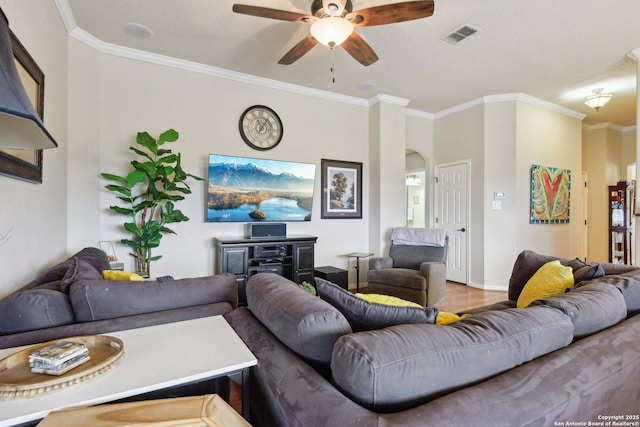 living area featuring arched walkways, visible vents, wood finished floors, ceiling fan, and crown molding