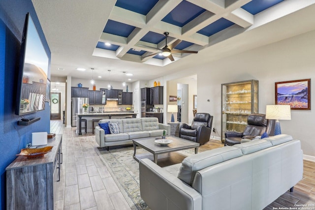 living area with ceiling fan, coffered ceiling, baseboards, wood finish floors, and beam ceiling