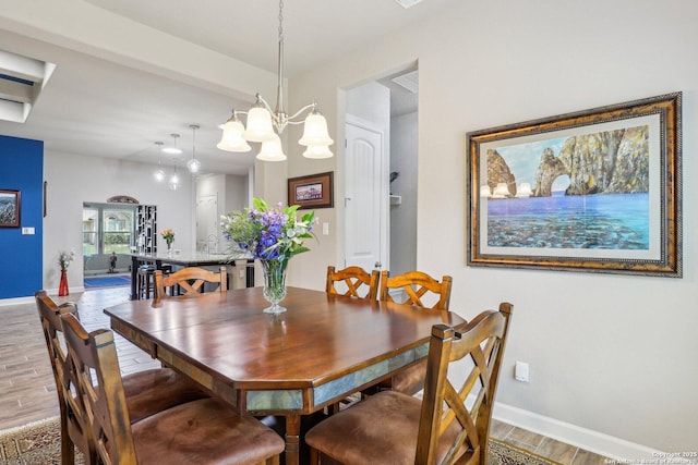 dining space featuring wood finished floors, baseboards, and a notable chandelier