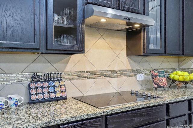 kitchen with decorative backsplash, black electric stovetop, glass insert cabinets, and extractor fan