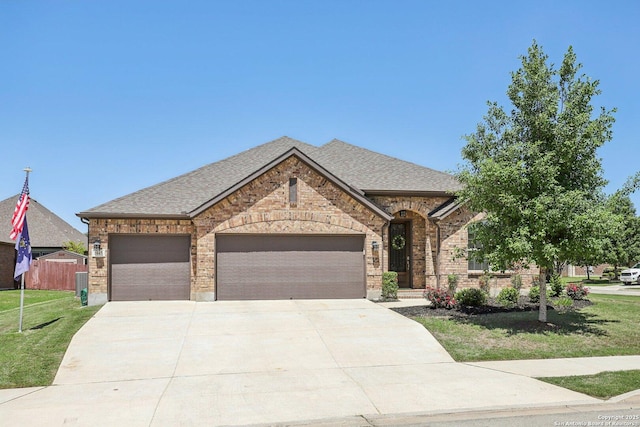 view of front of house featuring brick siding, roof with shingles, a front yard, and driveway