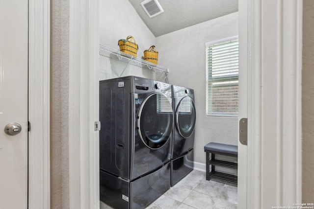 laundry area featuring tile patterned floors, laundry area, a textured wall, visible vents, and separate washer and dryer