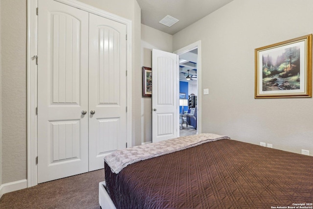 bedroom with dark colored carpet, visible vents, and a closet