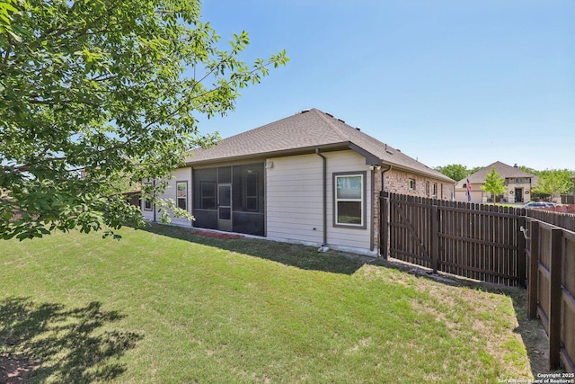 rear view of property with a fenced backyard, a yard, and a shingled roof