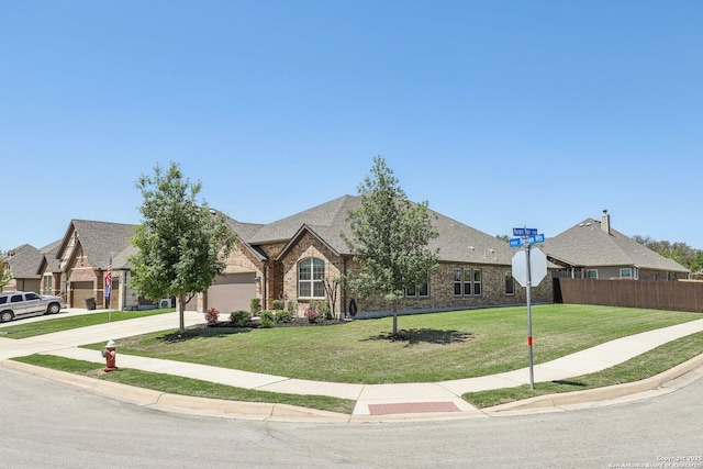 view of front of home with an attached garage, driveway, a front yard, and fence