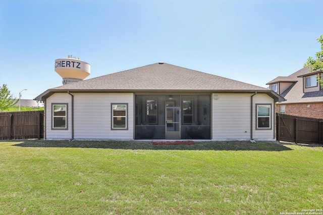 rear view of property featuring a fenced backyard, a sunroom, a yard, and roof with shingles
