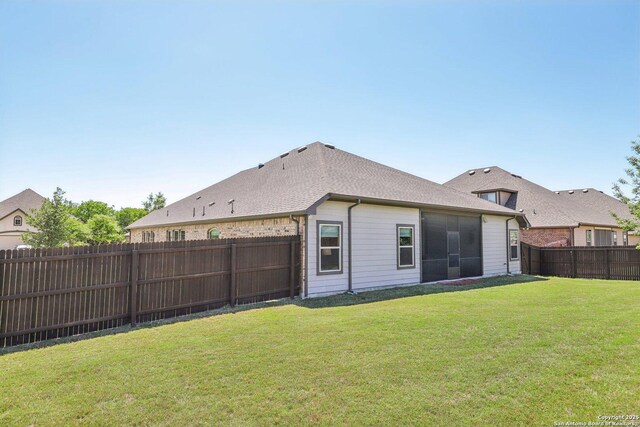 rear view of house with a lawn, a fenced backyard, and roof with shingles
