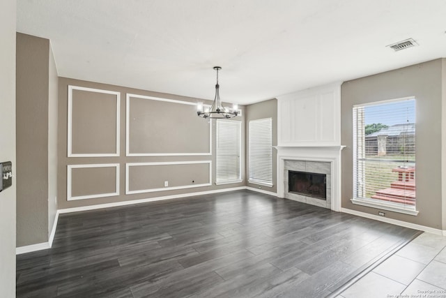 24915 Flying Arrow, San Antonio, TX 78258 - unfurnished living room featuring wood finished floors, visible vents, baseboards, and an inviting chandelier