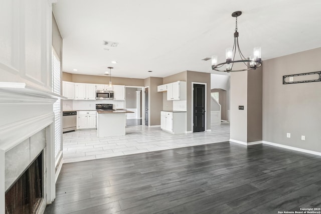 24915 Flying Arrow, San Antonio, TX 78258 - unfurnished living room with light wood finished floors, baseboards, visible vents, an inviting chandelier, and a fireplace