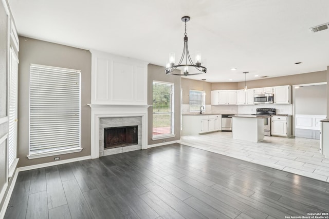 24915 Flying Arrow, San Antonio, TX 78258 - unfurnished living room with an inviting chandelier, a tile fireplace, light wood finished floors, visible vents, and recessed lighting