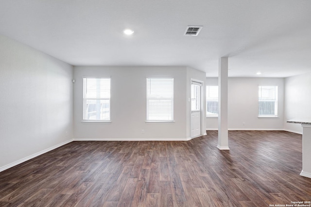 6551 Legato, San Antonio, TX 78252 - unfurnished living room with dark wood-style floors, a wealth of natural light, visible vents, and baseboards