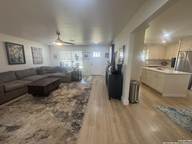 living room with ceiling fan, baseboards, visible vents, and light wood-type flooring