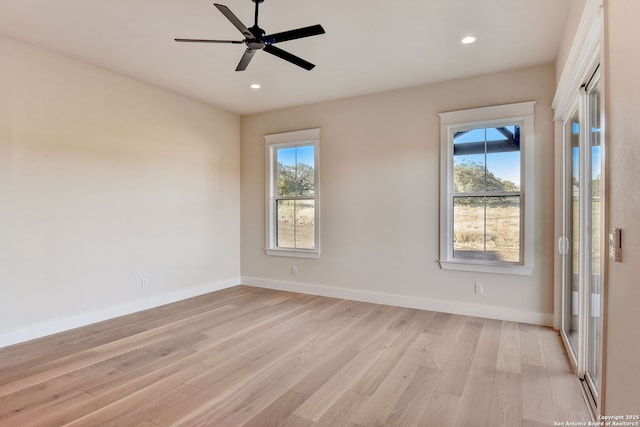 spare room featuring a ceiling fan, baseboards, a healthy amount of sunlight, and light wood-style floors