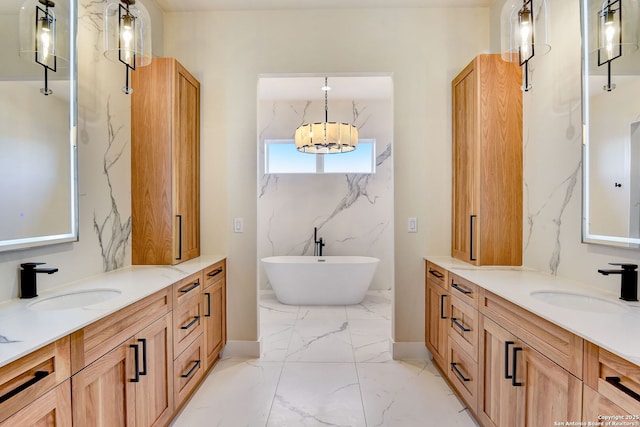 full bath with a freestanding tub, marble finish floor, a sink, and two vanities