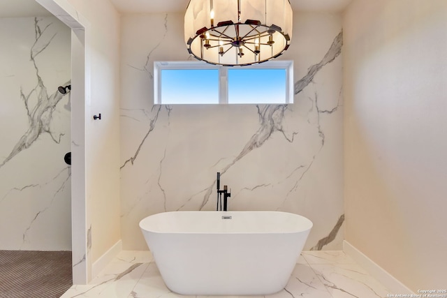 bathroom featuring marble finish floor, stone wall, and a soaking tub