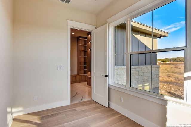 unfurnished room featuring baseboards, wood finished floors, and visible vents