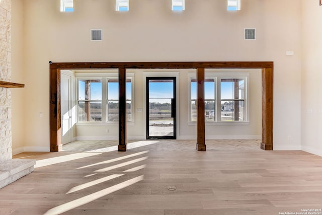 interior space with light wood-type flooring, visible vents, and a towering ceiling