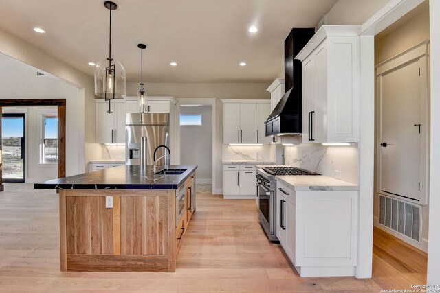 kitchen featuring a sink, light wood-type flooring, stainless steel appliances, baseboards, and visible vents