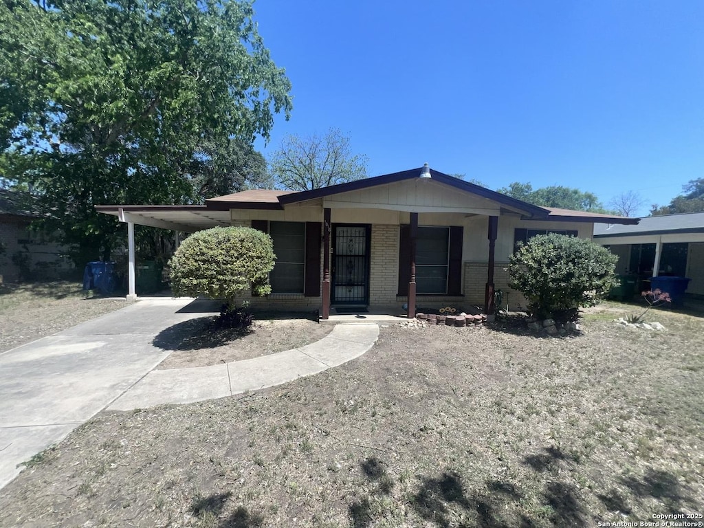 view of front of home featuring a porch, brick siding, an attached carport, and concrete driveway