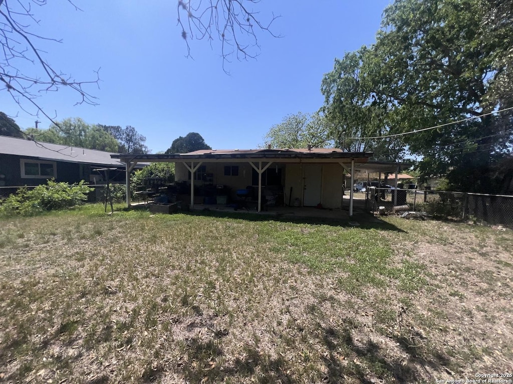 back of property featuring fence, a lawn, and a patio
