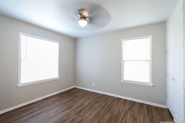 unfurnished room featuring a ceiling fan, baseboards, and dark wood finished floors