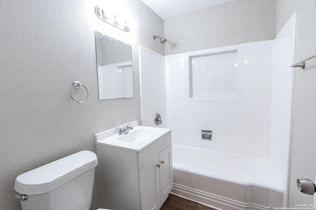 full bath featuring bathing tub / shower combination, toilet, wood finished floors, a textured wall, and vanity