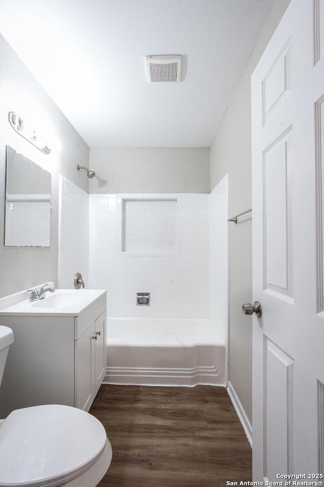 full bathroom featuring wood finished floors, vanity, toilet, visible vents, and bathing tub / shower combination