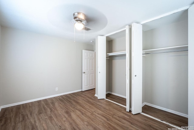 unfurnished bedroom featuring a ceiling fan, wood finished floors, two closets, baseboards, and visible vents